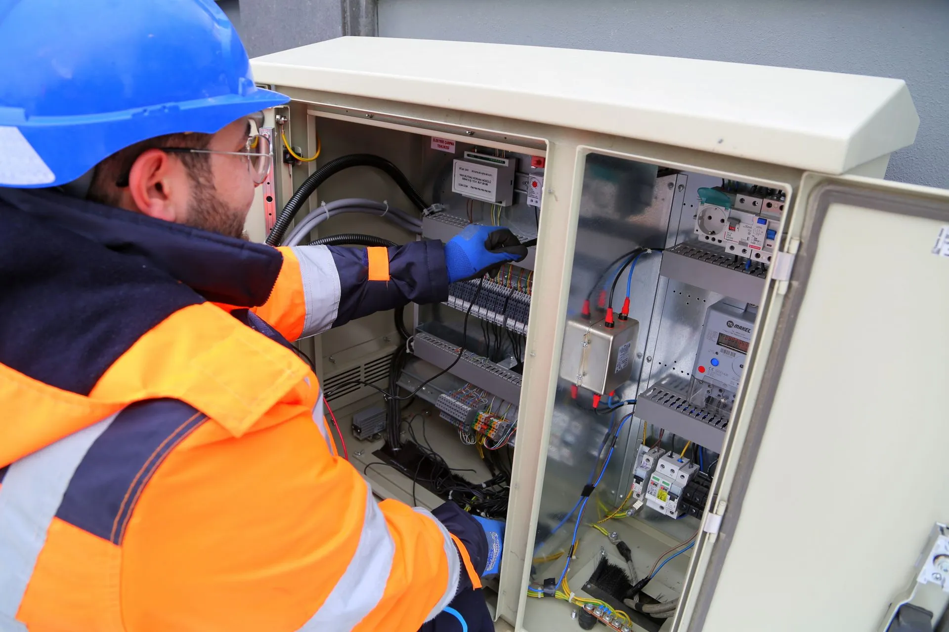 Technician in safety gear working on an electrical panel